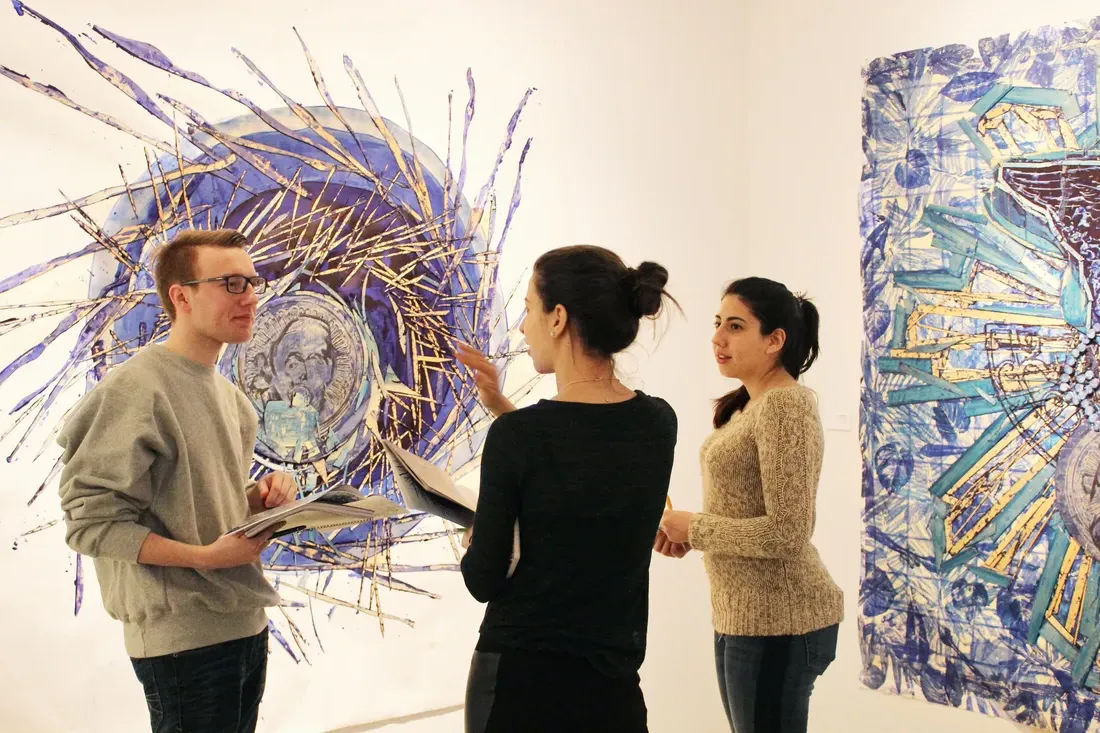 Three students talking in the Point of Contact gallery.